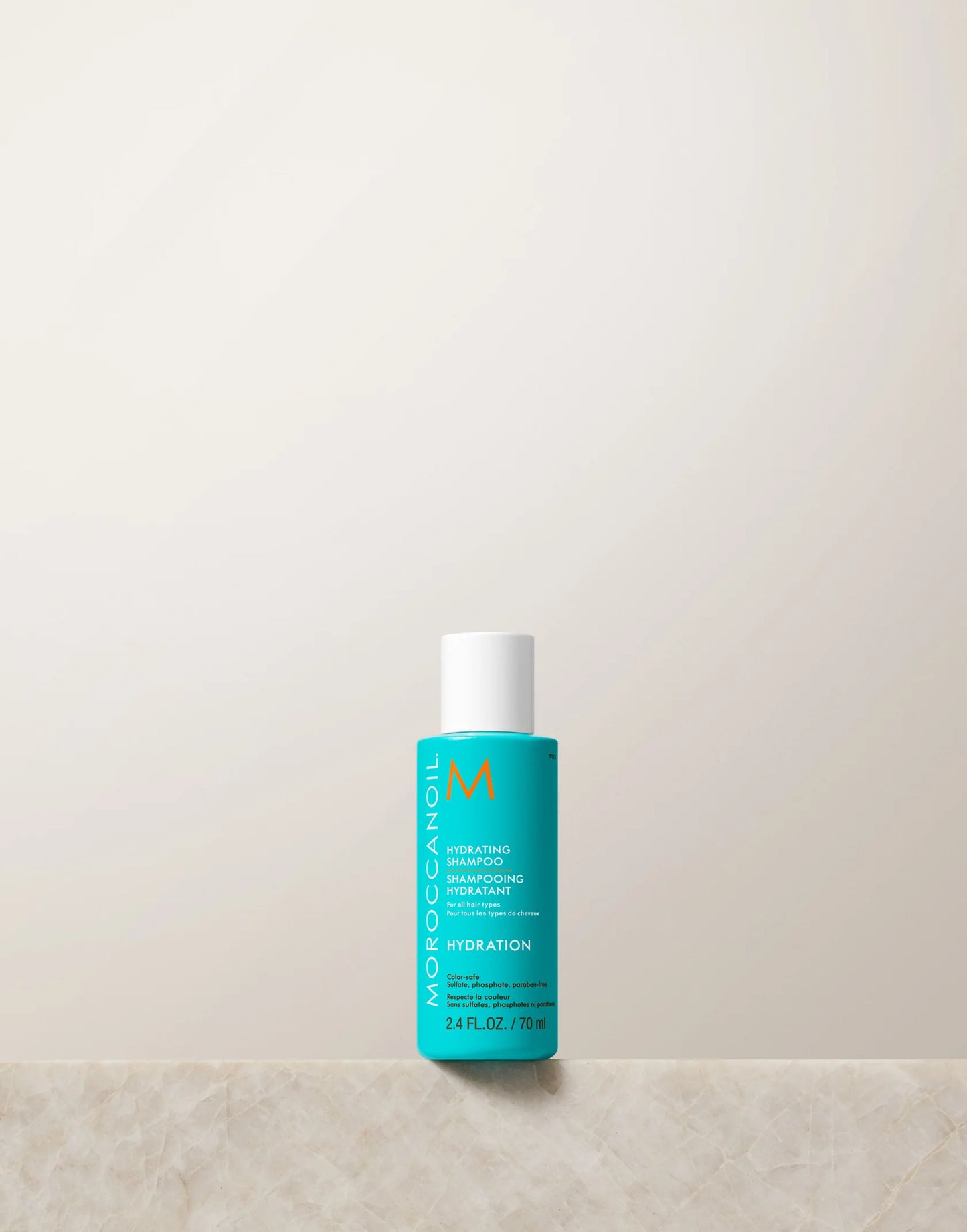 Blue bottle of Moroccanoil product on a light beige background