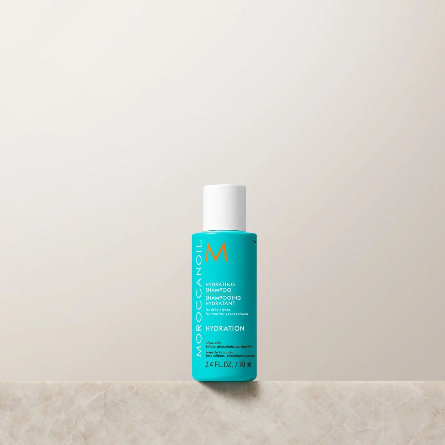 Blue bottle of Moroccanoil product on a light beige background
