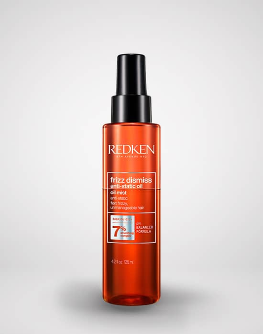 Redken hair oil bottle on a light gray background
