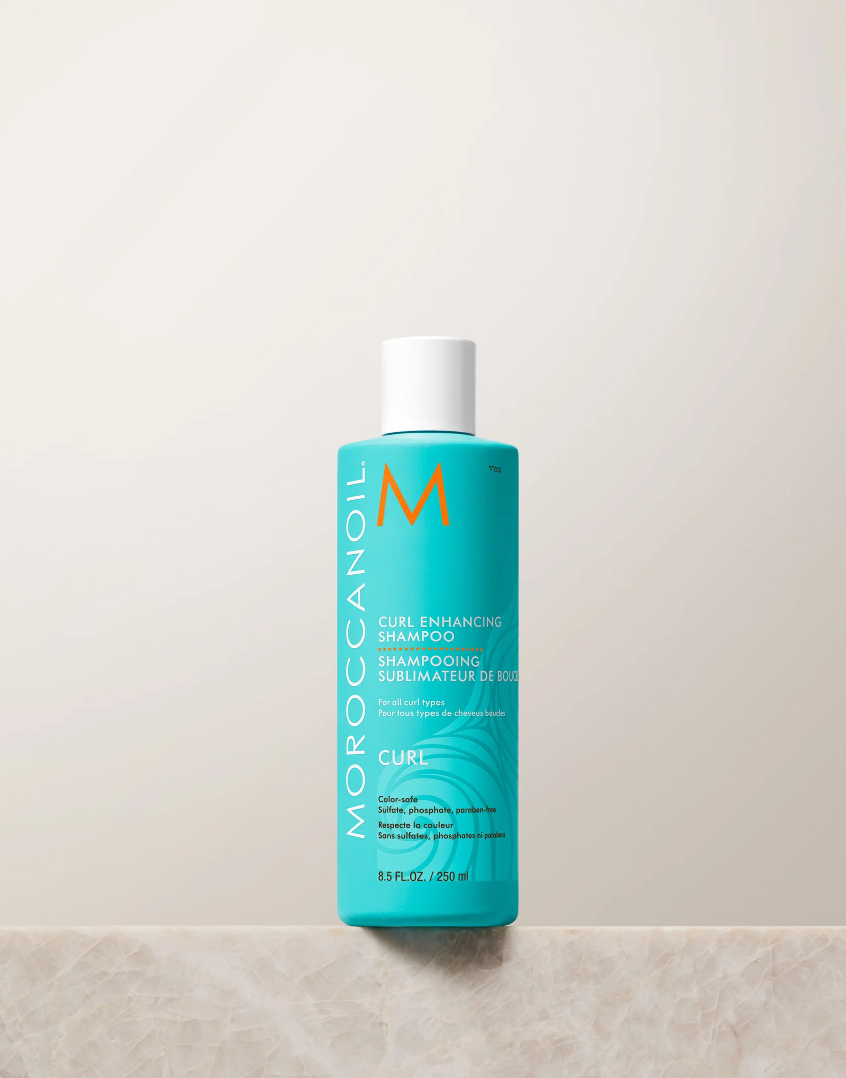 Moroccanoil bottle of Curl Enhancing Shampoo on a light beige background