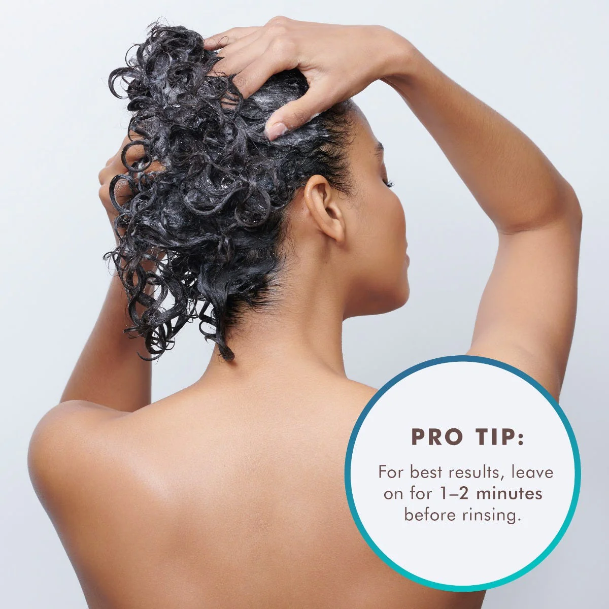 Woman with curly hair applying a product, with a pro tip overlay on a light gray background