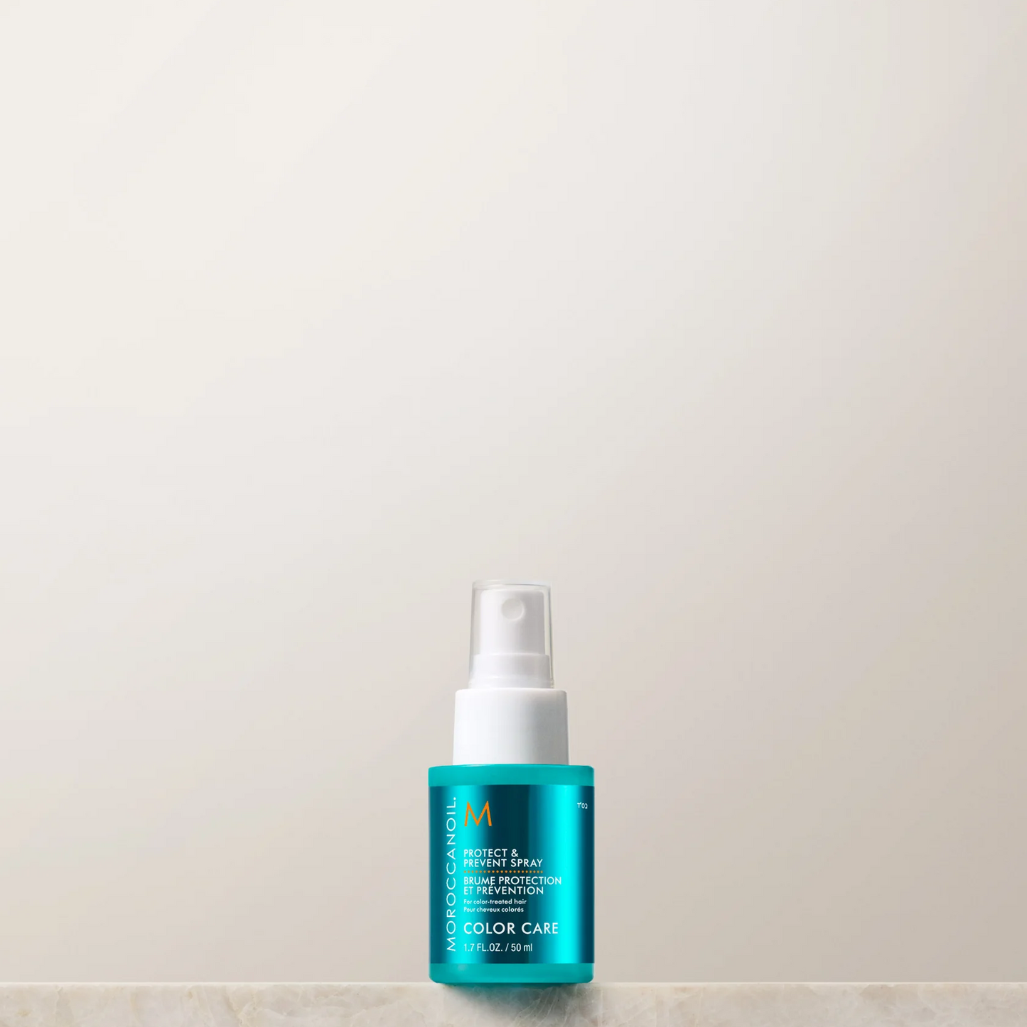 Blue spray bottle with white nozzle on a light beige background