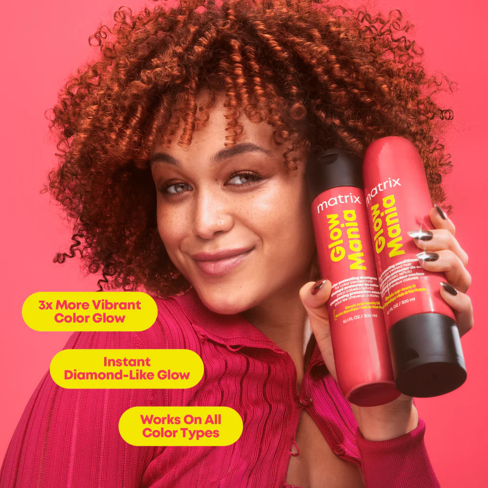 Woman holding Matrix Even Mona hair care products against a pink background
