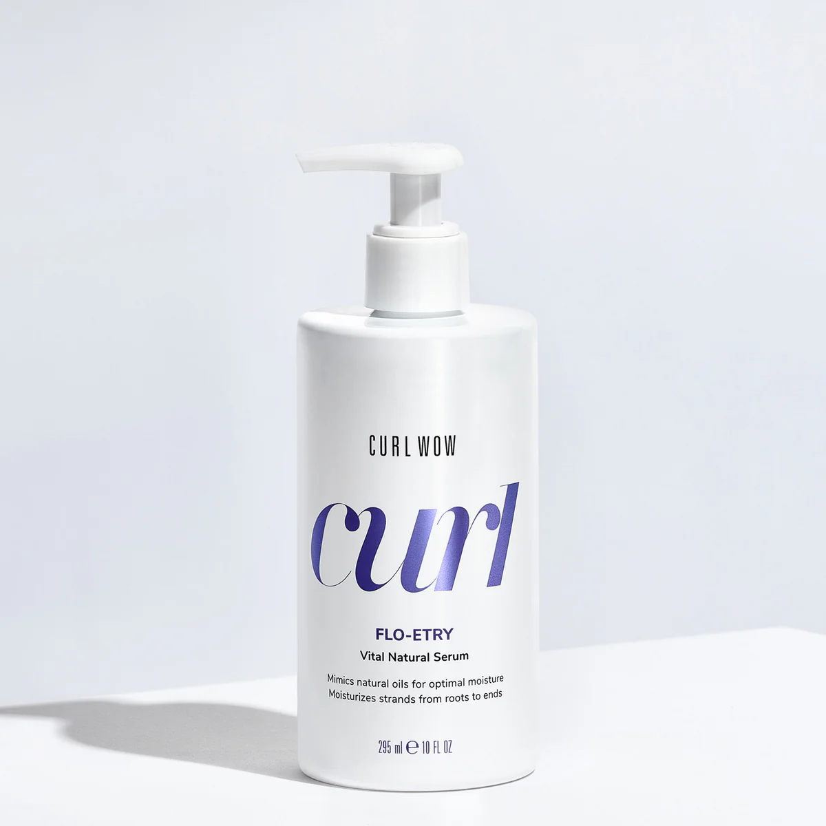 White bottle of Curl Wow Flo-Etry serum on a light gray background