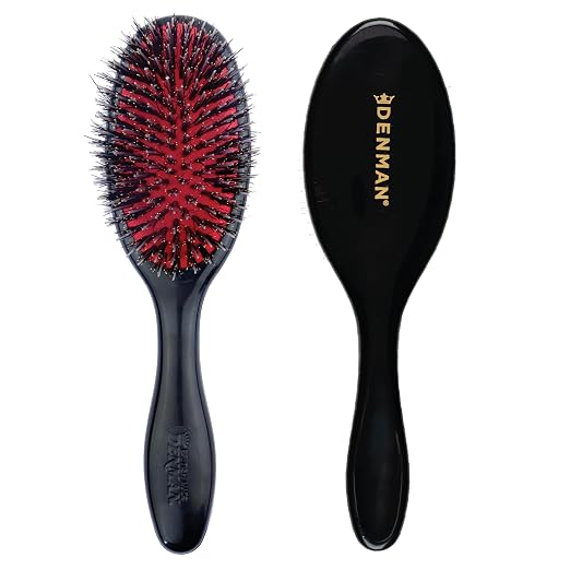 Two black hairbrushes shown side by side on a white background, one displaying the red and black bristles and the other showing the back with gold DENMAN branding.