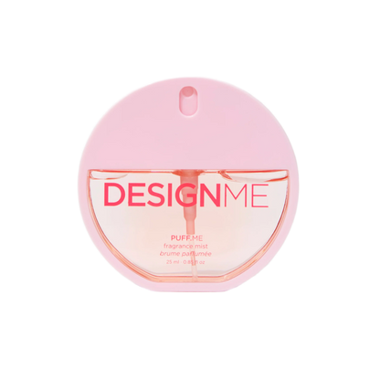A pink circular bottle of DESIGN ME Puff Me fragrance mist on a solid white background.