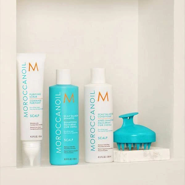 Moroccanoil hair care products including shampoo, conditioner, and scalp massager on a white surface.