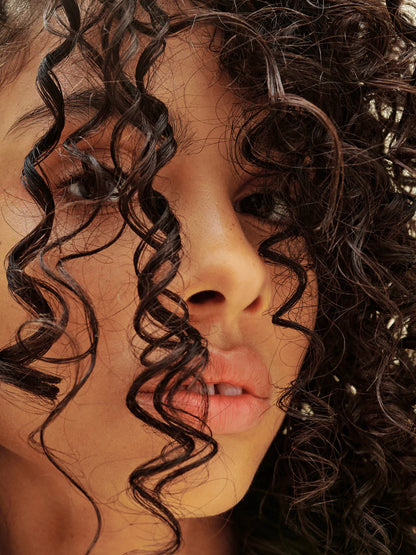 Close-up of a person with curly hair used AG Details curl defining cream