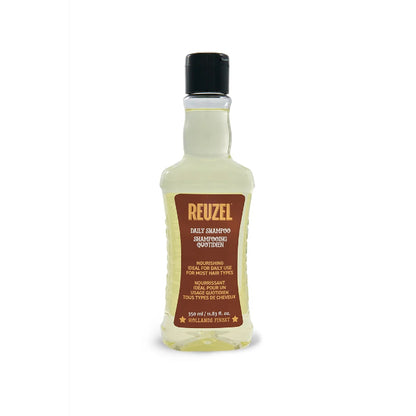 A 320 ml bottle of Reuzel Daily Shampoo Quotidien, featuring a clear plastic bottle filled with pale yellow liquid, a black cap, and a brown label with gold lettering.