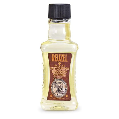 A bottle of Reuzel Daily Shampoo Quotidien, featuring a clear glass bottle filled with pale yellow liquid, a brown label with gold lettering, and a black cap, set against a plain white background.