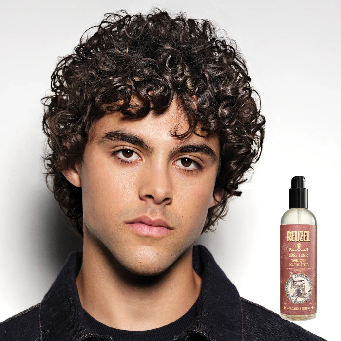 Man with styled hair next to a bottle of Reuzel product on a white background