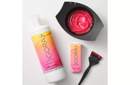 A Schwarzkopf GORA Vibrance hair color kit on a white background, including a bottle of activator lotion, a bowl of vibrant pink developer, a small box, and a brush.