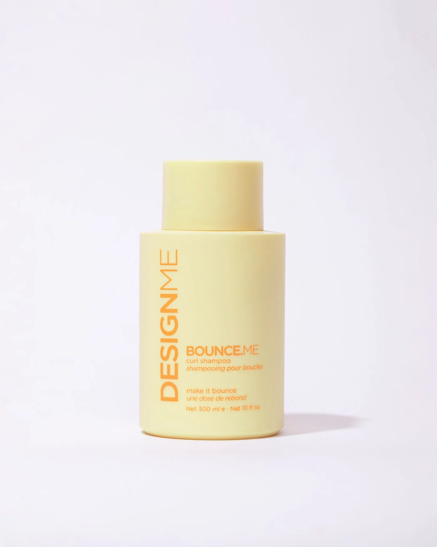 Yellow bottle of DESIGNME Bounce Me shampoo travel size on a white background