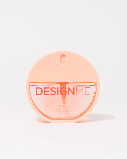A round, translucent peach-colored perfume bottle labeled 'DESIGNME HOLD ME' on a clean white background.