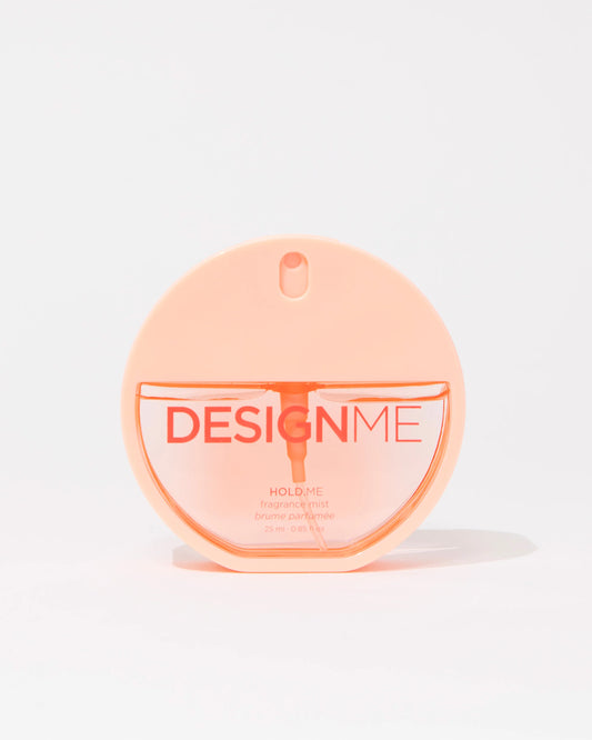 A round, translucent peach-colored perfume bottle labeled 'DESIGNME HOLD ME' on a clean white background.