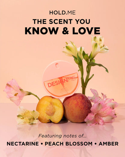A perfume bottle labeled DESIGN ME is arranged with peach blossoms and two peaches on a soft peach background, alongside text reading 'HOLD,ME THE SCENT YOU KNOW & LOVE' and 'Featuring notes of.
