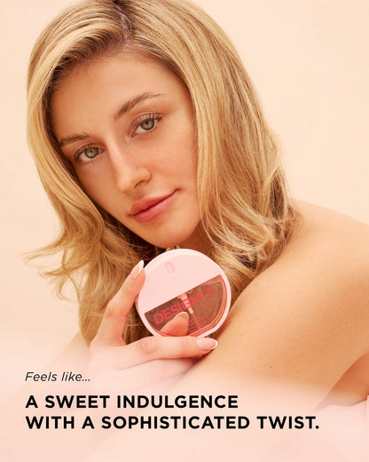 A blonde woman holding a round pink compact mirror with the brand name 'desire' visible on the lid, set against a soft peach background with promotional text at the bottom.