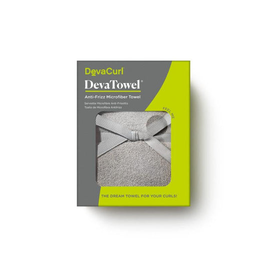 A boxed DevaCurl DevaTowel Anti-Friz Microfiber Towel shown on a white background. The retail package is gray and bright yellow-green, with a window revealing a light gray towel tied in a bow.