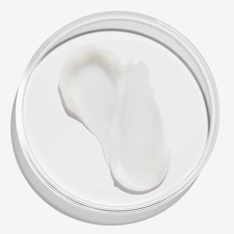 Jar of white cream with a visible scoop on a white background