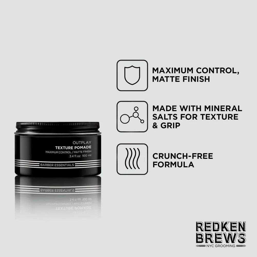 A black jar of Redken Outplay Textured Hair Styler matte finish pomade is shown on a light gray background with three feature callouts: maximum control and matte finish, made with mineral salts for texture and grip, and a crunch-free formula. The Redken Brews logo appears in the bottom right corner.