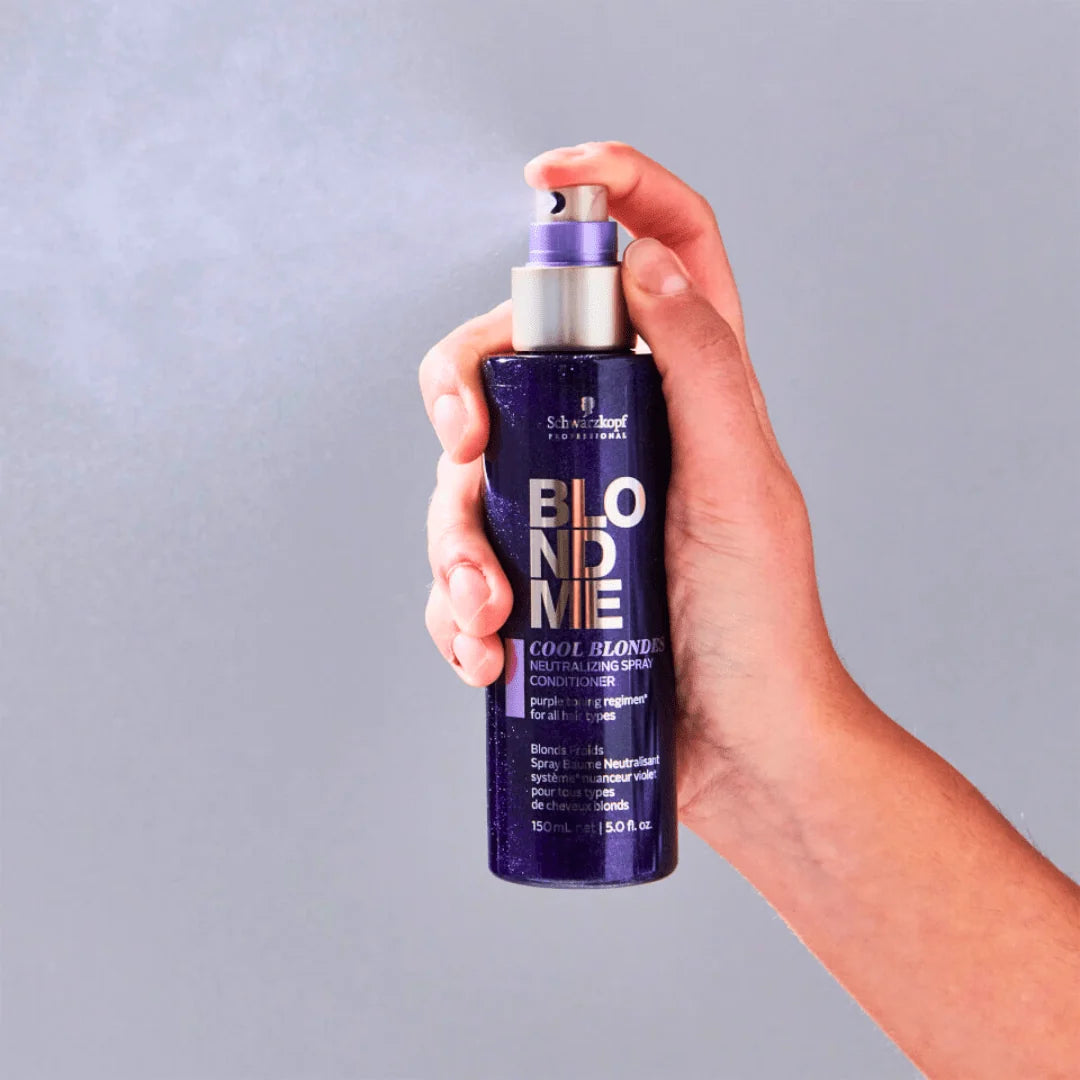 A hand holding a bottle of Shiseidos Blond Me Cool Blonde Conditioner against a solid gray background.